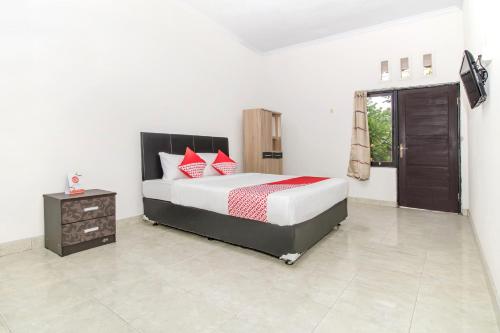 een slaapkamer met een groot bed met rode kussens bij OYO 2984 Berlian House Ungasan in Jimbaran