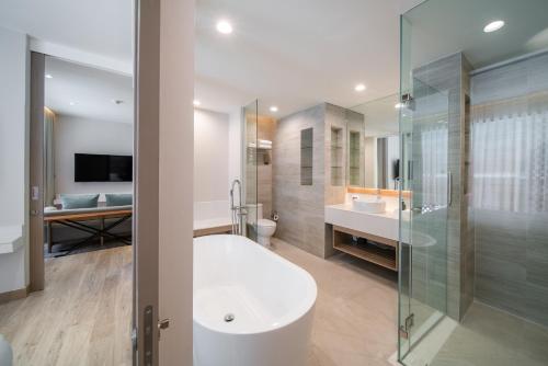 een badkamer met een bad, een wastafel en een douche bij Maven Stylish Hotel Hua Hin in Hua Hin