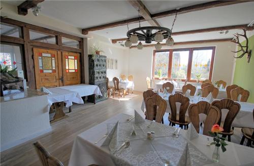ein Esszimmer mit weißen Tischen, Stühlen und Fenstern in der Unterkunft Lechstedter Obstweinschänke in Bad Salzdetfurth