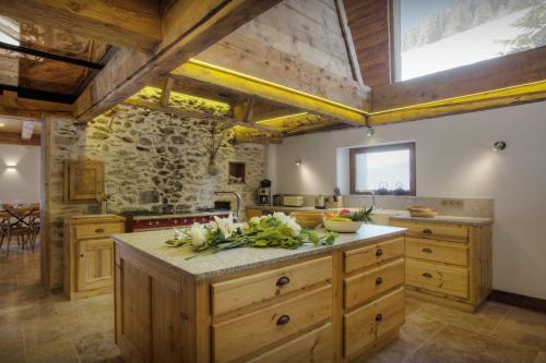 a kitchen with wooden cabinets and a stone wall at Chalet Goville - OVO Network in La Giettaz