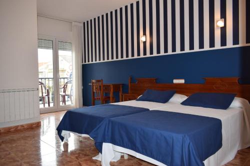 1 dormitorio con 2 camas y pared azul en Hotel VIDA Ostra Marina, en Sanxenxo