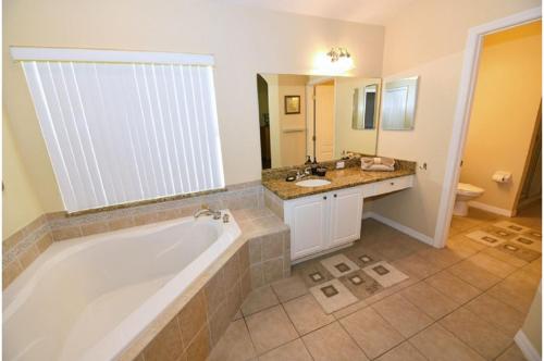 a bathroom with a tub and a sink and a toilet at Four-Bedroom Pool Home Davenport in Davenport
