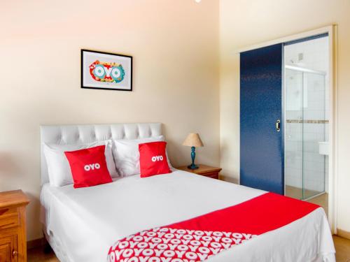 um quarto com uma grande cama branca com almofadas vermelhas em OYO Pousada Estrada Das Águas, São João del Rei em São João del Rei