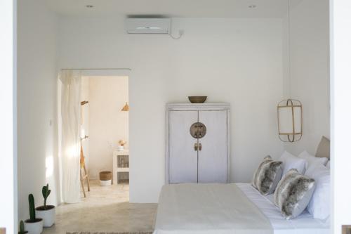 biała sypialnia z łóżkiem z białymi ścianami w obiekcie The Wabi Bali w mieście Canggu