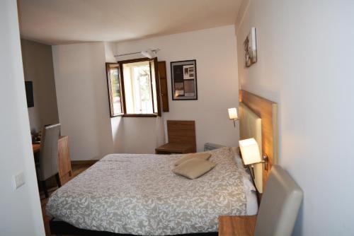 a small bedroom with a bed and a window at Le Grand Hôtel Molière in Pézenas