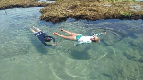 two people swimming in the water in the ocean at Beach Wind Hotel in Flecheiras