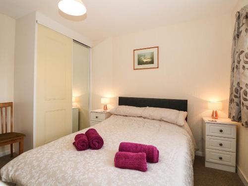 a bedroom with a bed with two pink towels on it at Penelope in Benllech