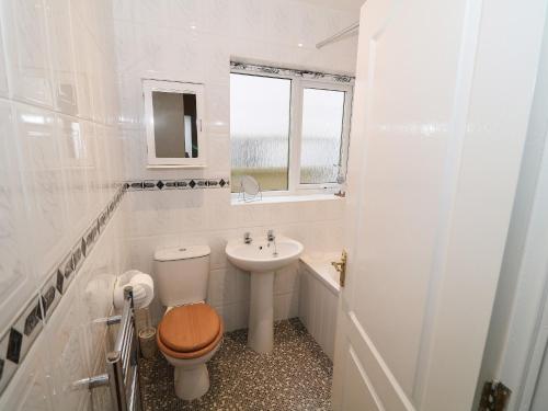 a white bathroom with a toilet and a sink at Penelope in Benllech