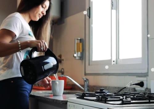 a woman standing in a kitchen with a tea kettle at eSuites Dalmacio Vélez 571 in La Rioja