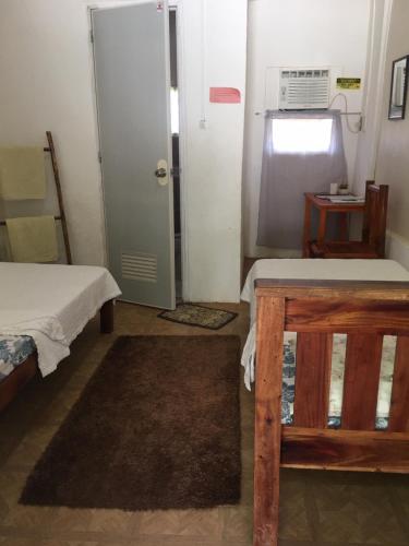 a room with two beds and a door and a table at DN Lodge 2 in Daanbantayan