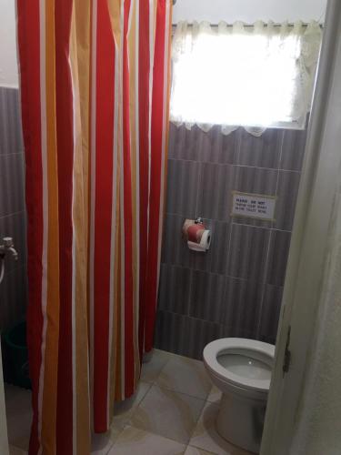 a bathroom with a toilet and a red and white shower curtain at DN Lodge 2 in Daanbantayan