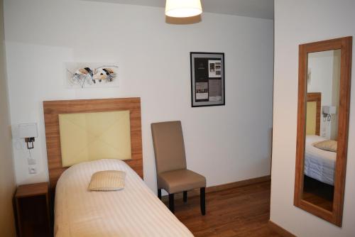 a bedroom with a bed and a chair and a mirror at Le Grand Hôtel Molière in Pézenas