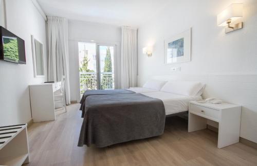 a white bedroom with a bed and a window at Hotel Garbi Park & AquaSplash in Lloret de Mar