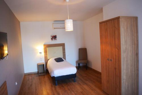 a bedroom with a bed and a wooden cabinet at Le Grand Hôtel Molière in Pézenas