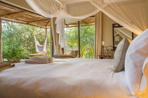 a bedroom with a large bed with a large window at Ukuthula Bush Lodge in Hoedspruit