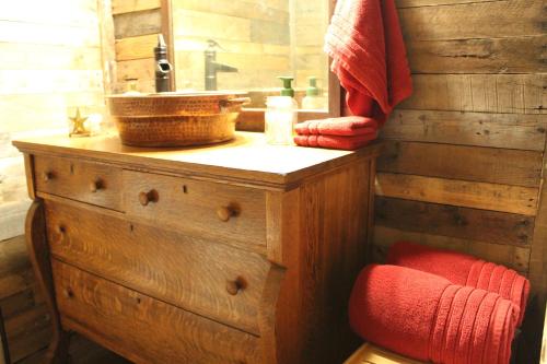 La salle de bains en bois est pourvue d'un lavabo et d'une chaise rouge. dans l'établissement The Christmas Cabin, à Ozark