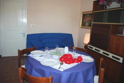 a table with a blue table cloth and red flowers on it at Casa Monti in Grado