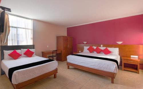 a hotel room with two beds with red pillows at Hotel San Pablo in Cholula