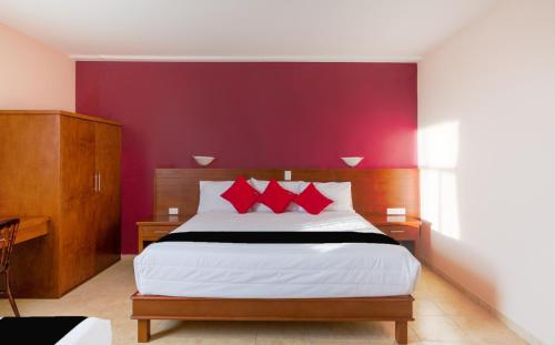 a bedroom with a large bed with red pillows at Hotel San Pablo in Cholula