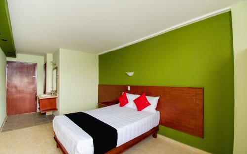 a bedroom with a bed with green walls and red pillows at Hotel San Pablo in Cholula