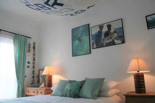 een slaapkamer met een bed en foto's aan de muur bij Modern Two Bedroom Poolside Townhouse in Budens
