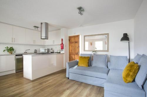 ein Wohnzimmer mit einem blauen Sofa und einer Küche in der Unterkunft Modern Grassmarket Apartment in Edinburgh