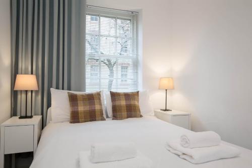 a bedroom with a white bed with two lamps at Modern Grassmarket Apartment in Edinburgh