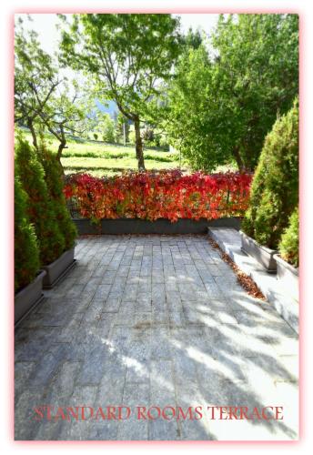 a garden with red and red flowers and trees at Hotel Beau Sejour in Etroubles