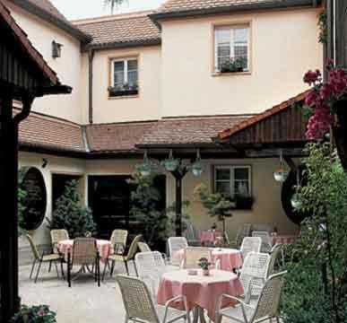 a patio with tables and chairs in front of a house at Hotel Altdeutsche Weinstuben in Freyburg