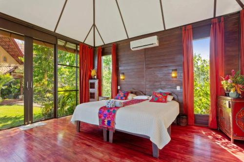 a bedroom with a bed and large windows at Anamaya Resort in Montezuma