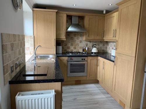 une cuisine avec des armoires en bois et un four à plaques de cuisson dans l'établissement Castle Cottage, à Harrogate
