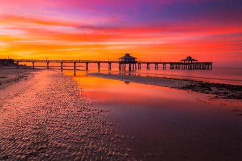 a pier on the beach with a sunset at San Carlos Paradise! in Fort Myers
