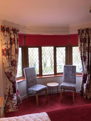 two chairs and a table in a room with windows at Ros Dún House in Donegal