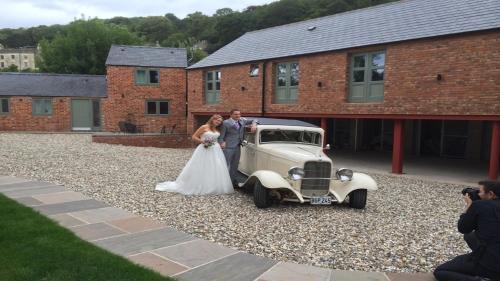 a bride and groom standing next to an old car at Railway Apartments in Nailsworth