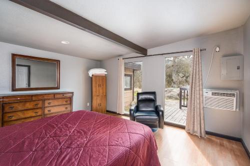 a bedroom with a bed and a chair and a window at Mountain Trail Lodge and Vacation Rentals in Oakhurst