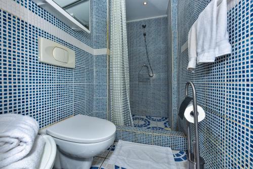a blue tiled bathroom with a toilet and a shower at Sunflower Villa Studios in Palm-Eagle Beach