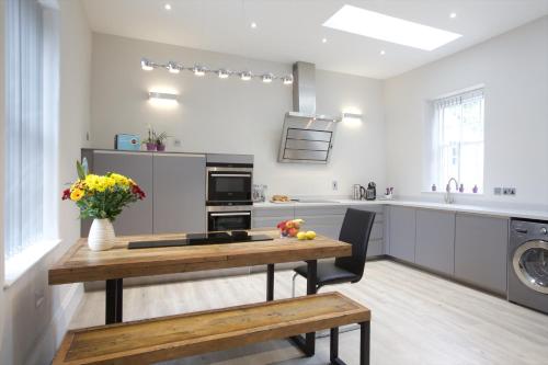 a kitchen with a wooden table with flowers on it at Railway Apartments in Nailsworth