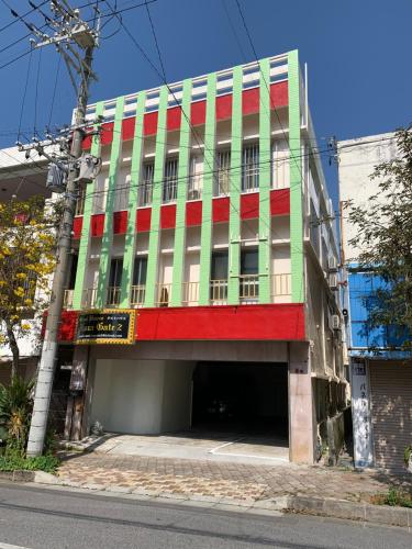 a green and red building with a parking garage at Guest House Koza Gate2 in Okinawa City
