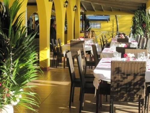 un comedor con mesas, sillas y plantas en Paradise Beach Hotel, en Kingstown