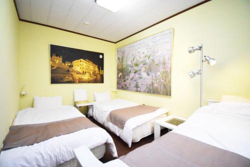 Una habitación con tres camas y un cuadro en la pared. en Oasis Minamiyukigaya, en Tokio
