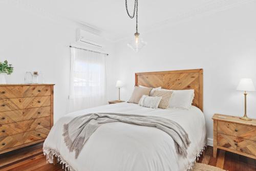 a white bedroom with a large bed with a wooden headboard at The Cottage on Lamington in Canungra
