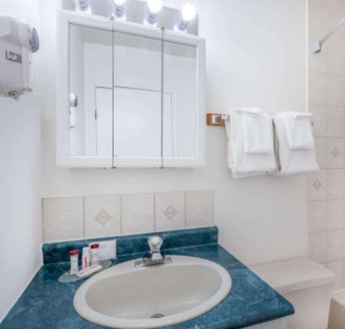 ein Badezimmer mit einem Waschbecken, einem Spiegel und Handtüchern in der Unterkunft Almada Inn in Fort Nelson