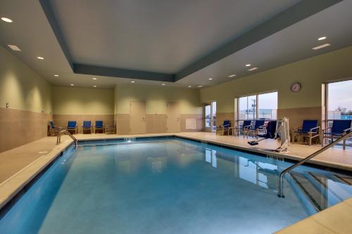 a large swimming pool in a room with chairs at Holiday Inn Express & Suites Troy, an IHG Hotel in Troy