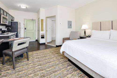 a hotel room with a bed and a desk and a kitchen at Candlewood Suites Dallas NW - Farmers Branch by IHG in Farmers Branch