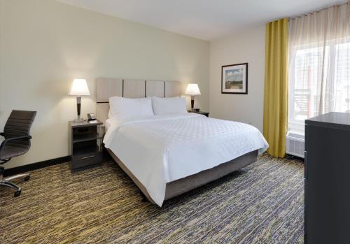 a hotel room with a bed and a desk and chair at Candlewood Suites Dallas NW - Farmers Branch by IHG in Farmers Branch