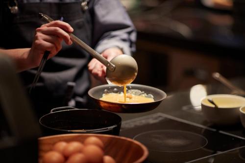 a person cooking food in a pan on a stove at Hyatt Centric Ginza Tokyo in Tokyo
