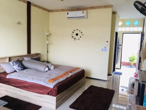 a bedroom with a bed and a clock on the wall at Touch the Wind in Chaiyaphum