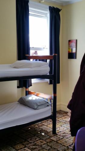 two bunk beds in a room with a window at Empire Hotel Backpackers in Oamaru