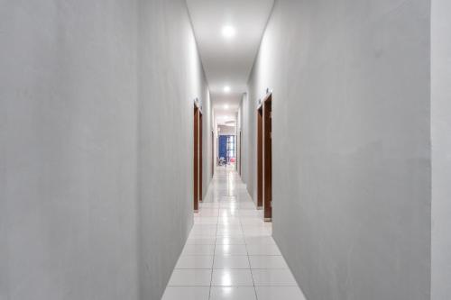 a hallway with white walls and a white tile floor at RedDoorz near Manhattan Square Medan in Pulauberayan