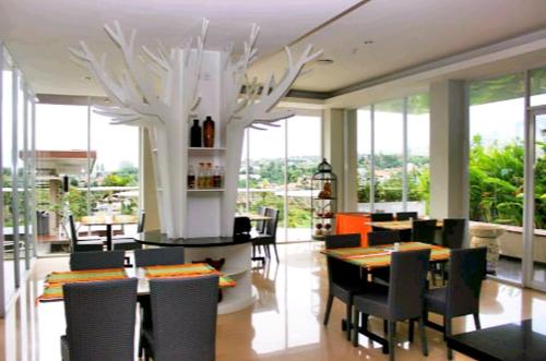a dining room with a table and chairs and windows at Moscato Hotel in Lembang